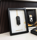 Framed model cars of Lamborghini Urus and Nissan GT-R on a white surface with a dark textured background.